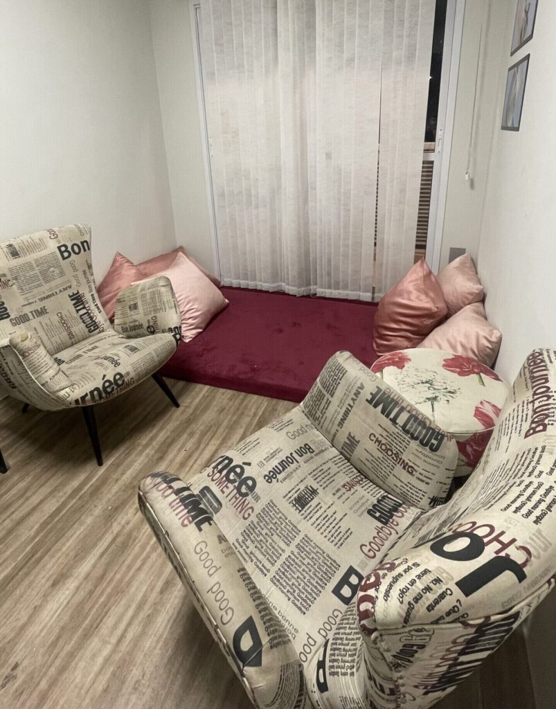 Sala para atendimento psicológico adulto com 2 poltronas uma de frente para outra e tapete com almofadas opcional para acomodação do paciente